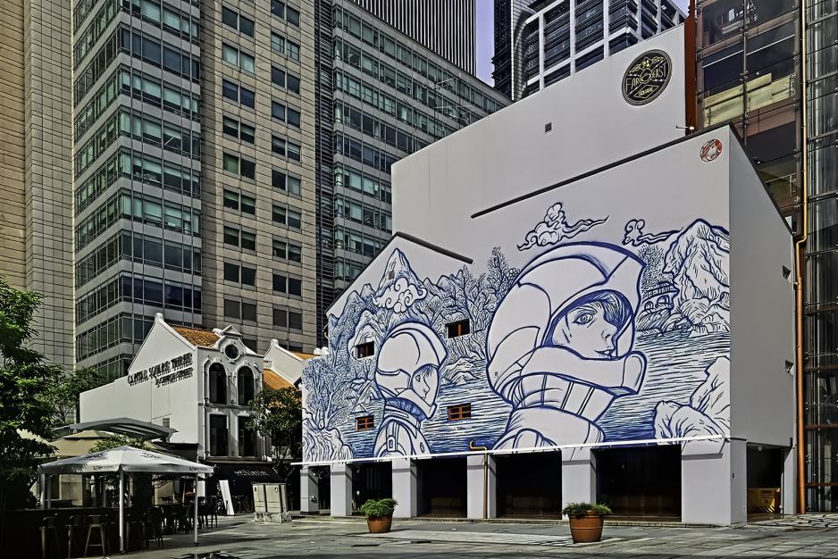 Photo of a mural of two astronauts painted on the side of a white building with blue lines 