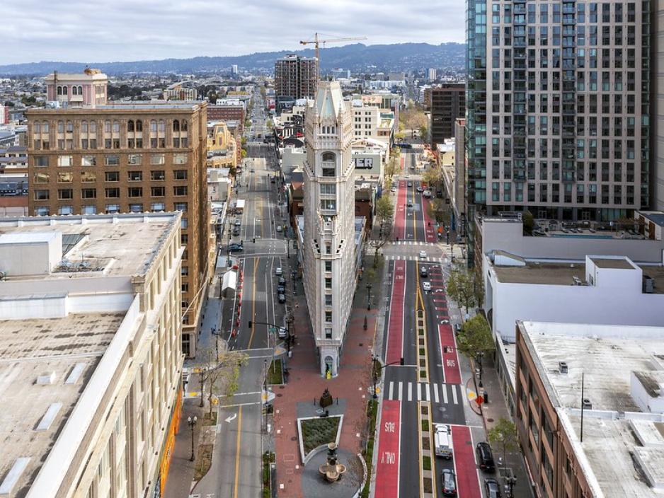 Photo from above many tall buildings looking down a roadway that splits partway through with red bus only lanes on one side and a pedestrian plaza in the center