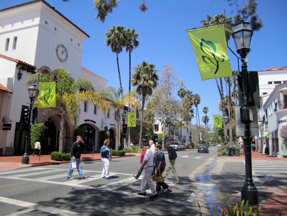 A photo of a main street with people walking in a crosswalk.