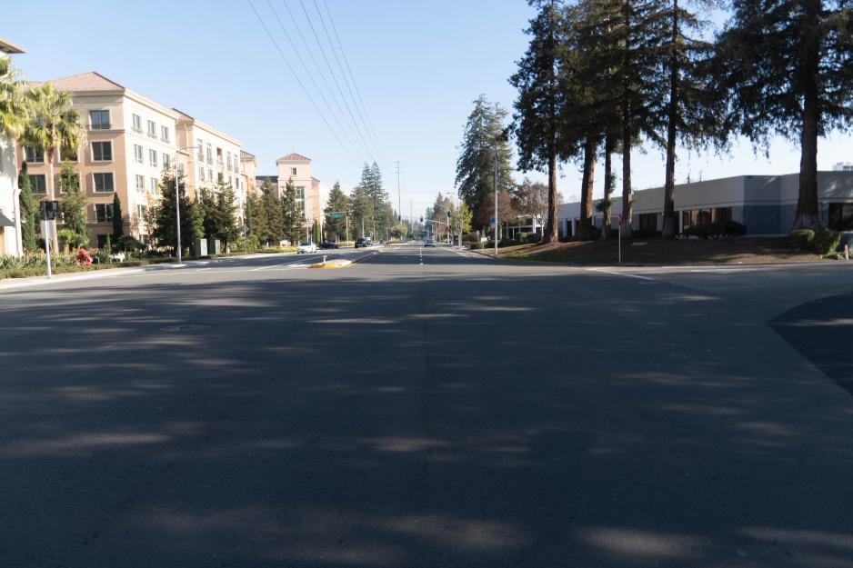 A photo of a four lane street with a business area and an apartment around.