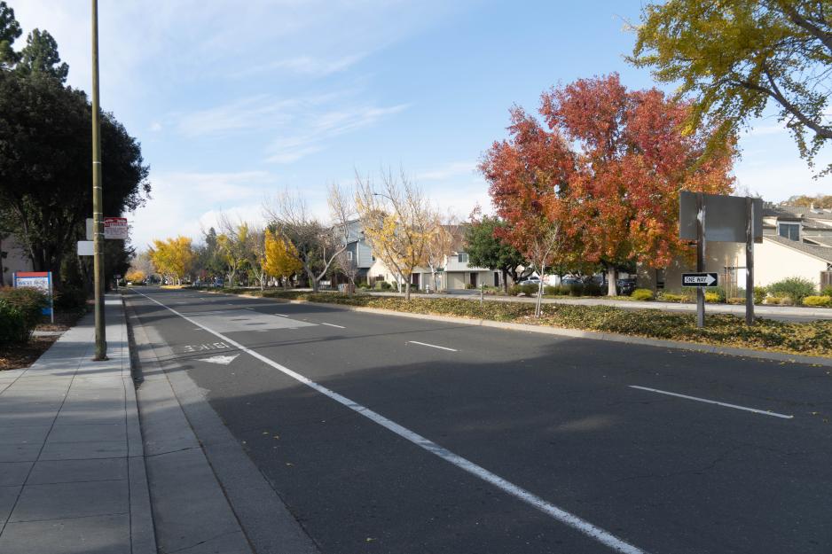 A photo of a street with a median, sidewalk, and bike lane. 