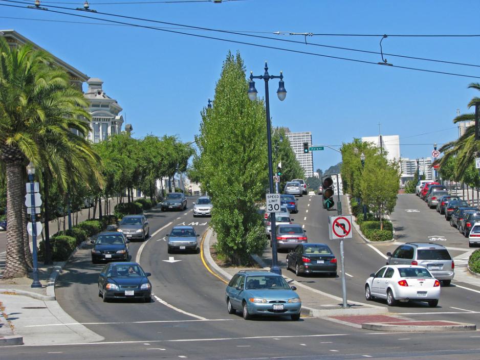 A photo of a busy street with a median with trees.