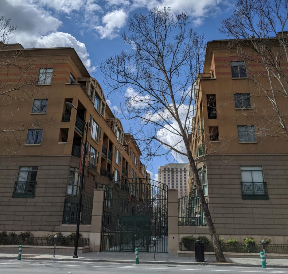 Two taller buildings surrounding a gated pedestrian walkway on a sunny day