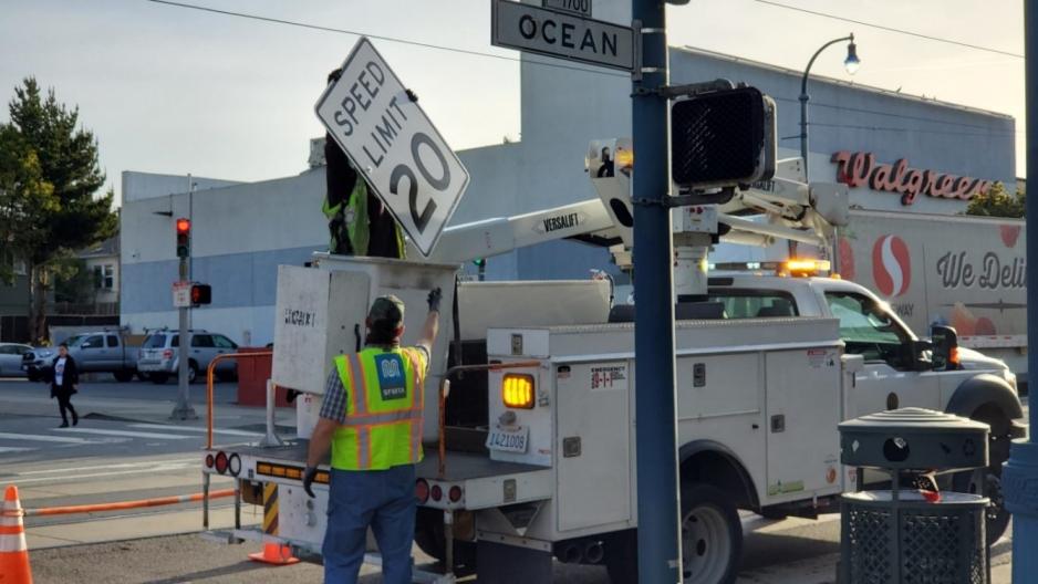 A photo of a 20 mile per hour speed limit sign being installed. 