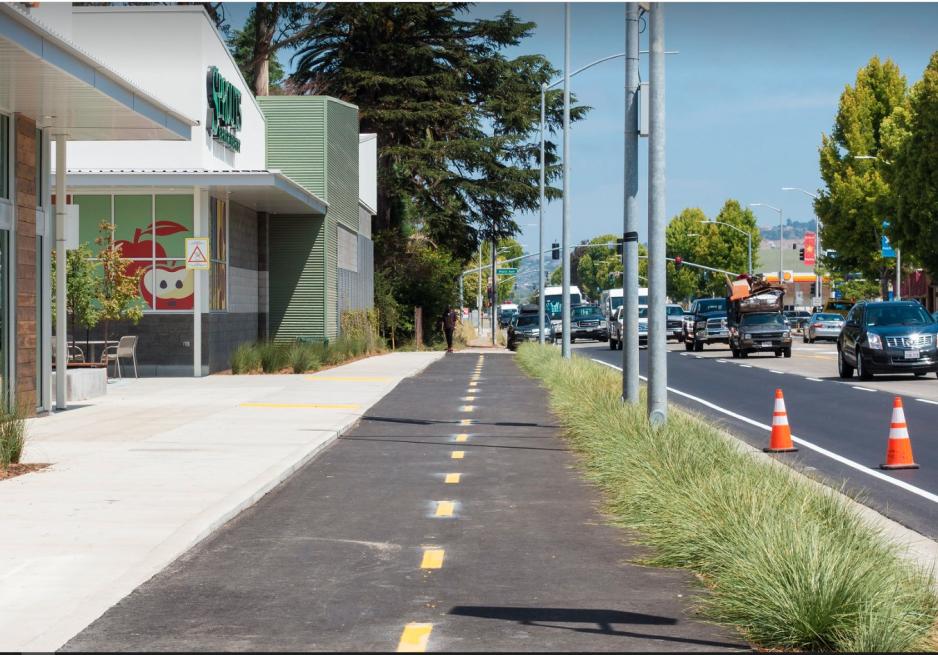 A photo of a separated bike lane next to a grocery store.