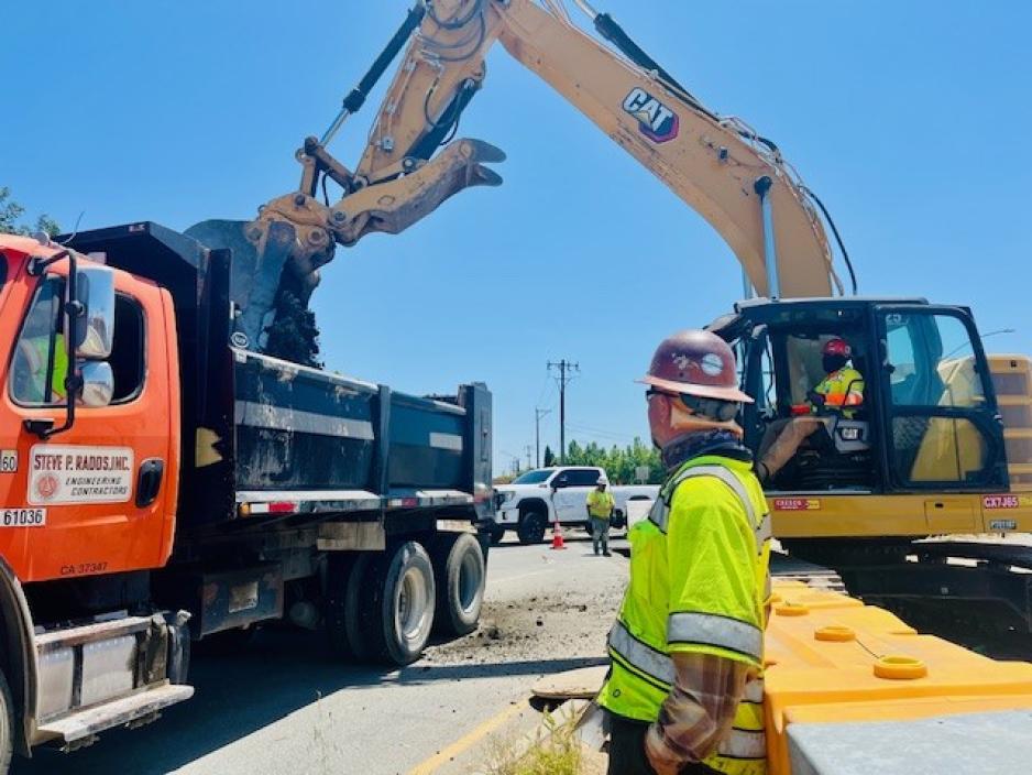 Construction worker, a large truck, and an excavator