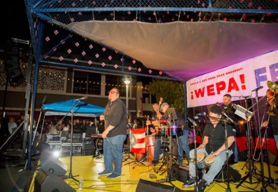 man standing on a stage singing with a band in the background