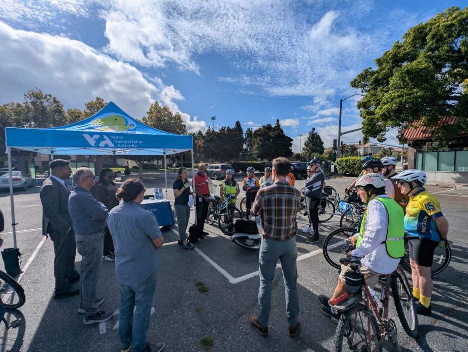 people in bike helmets and others standing in parking lot with bikes 