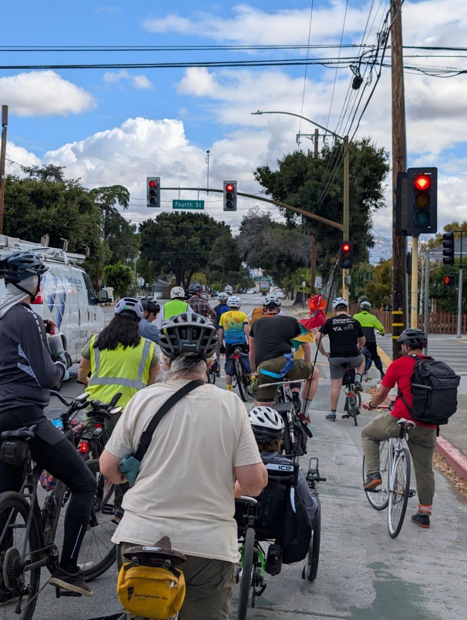 group of bicyclists waiting to cross the street at a red light