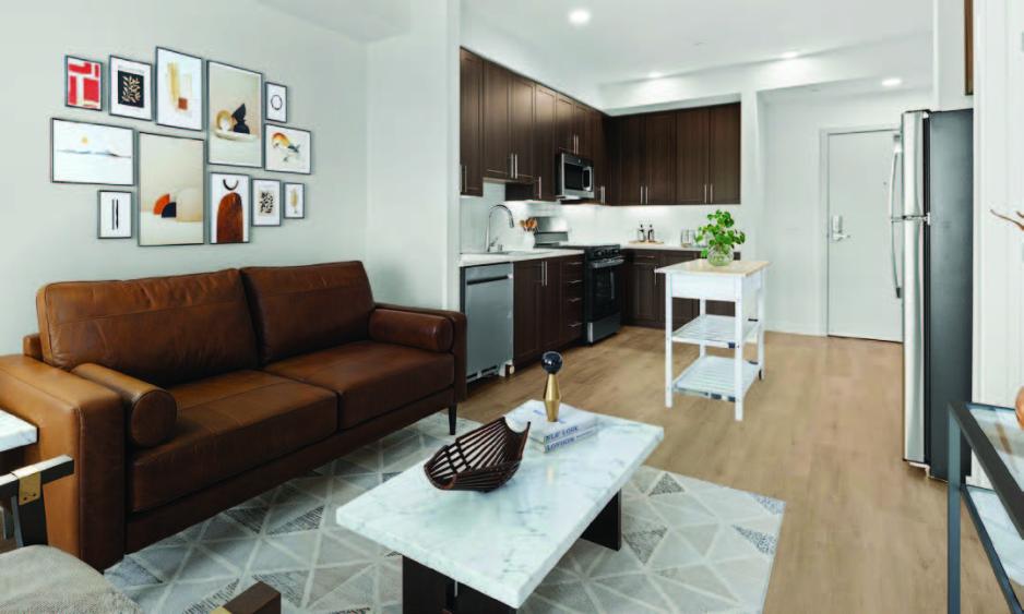 sofa and coffee table in living room, kitchen and front door in background