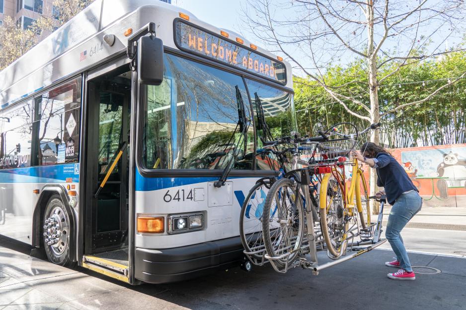Woman uploading bike onto bike rack on bus.