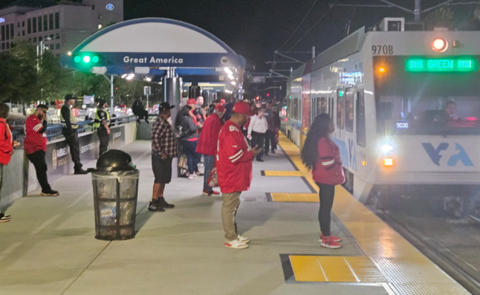 VTA riders waiting at the Great America light rail station for the green line with the new green light notifying them that the green line has arrived.